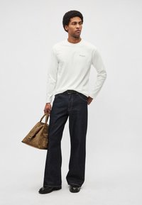 Balts garām piedurknēm krekls ar nelielu teksta logotipu, tumši zili platu kāju džinsi, melns josta, brūna ādas soma un melni apavi. Gluda tekstūra.