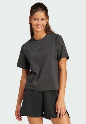 Camiseta de algodón negra de manga corta y cuello redondo, con un sutil logo en el pecho; combinada con pantalones cortos negros a juego.