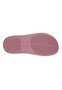 Suela de zapato Crocs en rosa suave. Presenta un diseño texturizado con marcas en forma de rayas y patrones circulares. Incluye la marca de tamaño "W 7" y el logotipo de la marca.