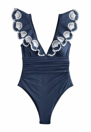 Granatowy jednoczęściowy kostium kąpielowy z głębokim dekoltem w serek i falbanami na ramionach, ozdobiony białymi haftowanymi wzorami muszelek.