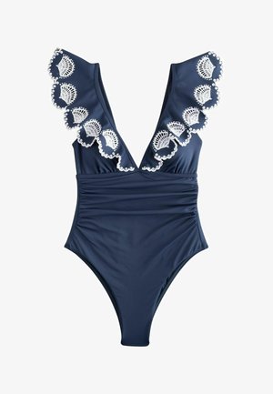 Tengerészkék egyrészes fürdőruha mély V-nyakkivágással és fodros vállrésszel, fehér hímzett kagylómintákkal díszítve.