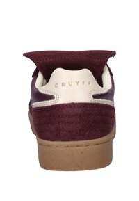 Bordeaux suède sneaker met een crèmekleurige leren hiel, voorzien van een ronde vorm, een bruine rubberen zool en een geperst logo op de hielkap.