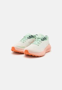 Zapatillas de running ligeras con parte superior de malla verde menta, suela de goma naranja y detalles en verde en el talón. Perforadas para mayor transpirabilidad.