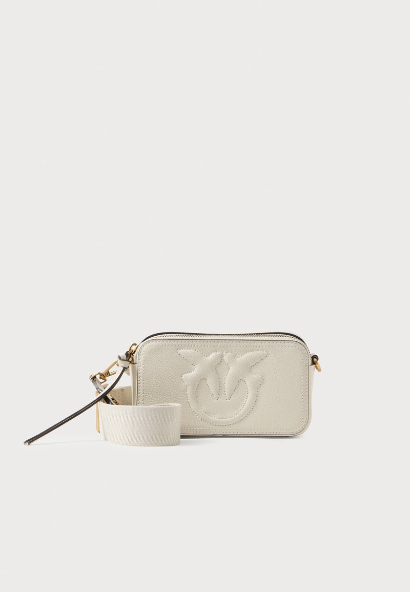 Bolsa crossbody retangular em couro creme com design embutido, fecho de zíper e alça destacável. Textura suave e detalhes de hardware discretos.