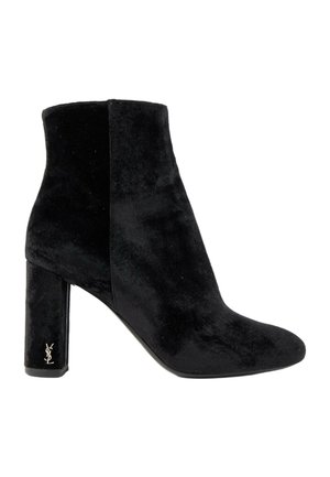 Bottine en velours noir avec talon carré et petit logo métallique YSL sur le côté du talon, vue de profil gauche sur fond blanc.
