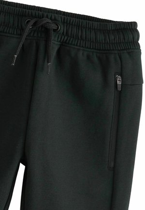 Pantaloni di felpa neri con vita elasticizzata e cordino. Presentano una tasca con zip sul lato. Realizzati in morbido tessuto testurizzato.