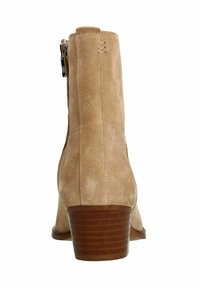 Stivaletto in pelle scamosciata beige con tacco in legno impilato, cerniera laterale e dettagli di cucitura sottili lungo il retro. Texture liscia in tutto il prodotto.