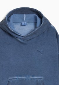 Niebieska bawełniana bluza z kapturem o miękkiej fakturze i subtelnym gradiencie. Posiada małe, haftowane logo Puma na piersi.