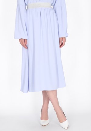 Vestido midi azul claro con mangas largas y una cinturilla elástica plateada, que presenta una tela suave y una silueta fluida. Tacones blancos de punta.