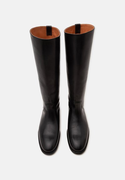Paire de bottes hautes en cuir noir avec bouts ronds et doublure intérieure beige, vues de dessus sur fond blanc.
