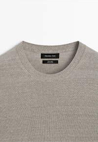 Jasnoszary sweter z lnu o okrągłym dekolcie marki Massimo Dutti z prążkowanym kołnierzem oraz widocznymi metkami z nazwą marki i materiału wewnątrz kołnierza.