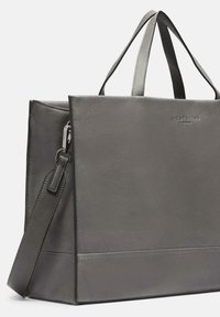 Szara skórzana torba tote z podwójnymi uchwytami u góry, regulowanym paskiem na ramię i subtelnymi teksturowanymi akcentami. Charakteryzuje się eleganckim, nowoczesnym wzornictwem.