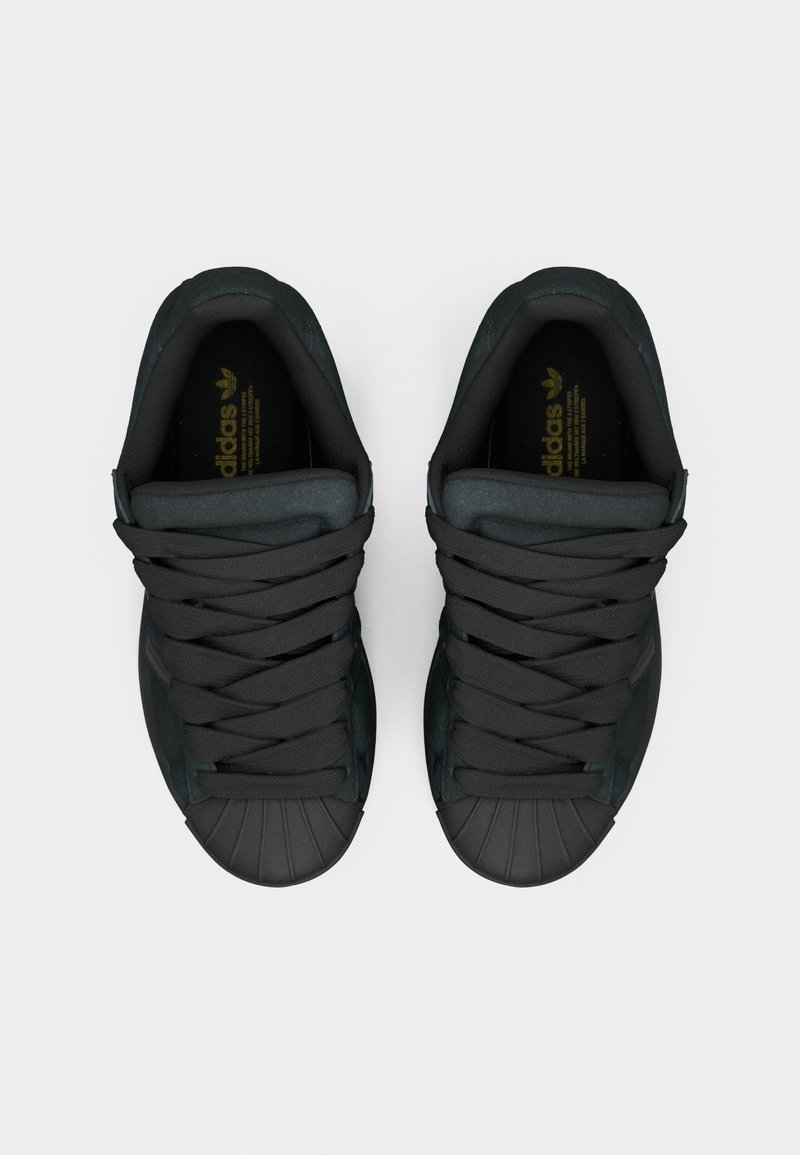 Baskets noires avec embout en caoutchouc, dotées de lacets épais noirs et d'une languette rembourrée. Accents de logo doré sur les semelles intérieures.