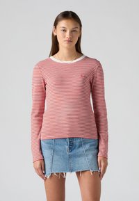Röd- och vitrandig långärmad skjorta med rund halsringning och en liten logotagg. Bärs tillsammans med en högmidjad jeanskjol.