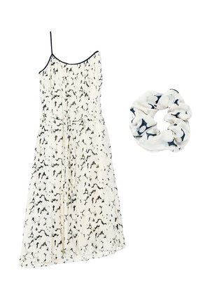 Robe sans manches blanche et noire à imprimé floral avec fines bretelles à côté d'un chouchou assorti avec un motif similaire noir et blanc.