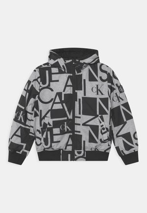 Veste à capuche noire et grise ornée de grandes lettres mélangées et de logos "cK" imprimés partout, avec fermeture éclair avant et poignets et ourlet côtelés.