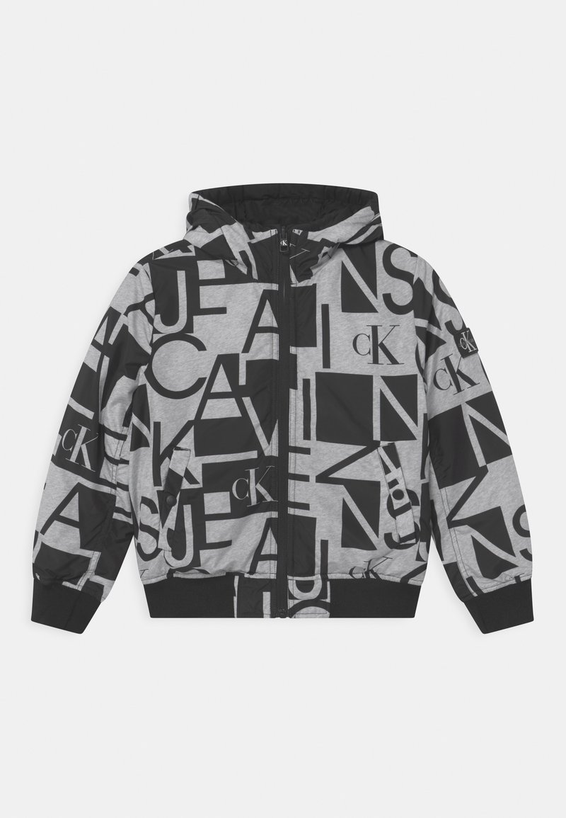 Chaqueta con capucha negra y gris con letras grandes mezcladas y logotipos "cK" impresos por todas partes, con cremallera en el frente y puños y dobladillo acanalados.