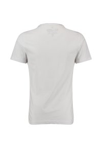 Camiseta blanca de manga corta vista desde la parte de atrás con una etiqueta impresa sutil cerca del escote.