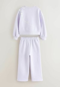 Lilla cropped sweatshirt med hvid grafisk design på ryggen, parret med matchende joggers med elastisk talje. Blødt materiale, afslappet pasform, elastisk talje.