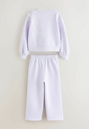 Sweat-shirt court violet avec un design graphique blanc au dos, assorti à un jogging élastique. Matériau doux, coupe décontractée, taille élastique.