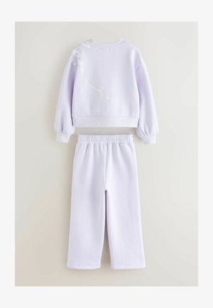 Ljubičasti skrajšani pulover s belim grafičnim dizajnom na hrbtu, uparen s odgovarajućim hlačama na elastiko. Mekan material, udoban kroj, elastični pas.