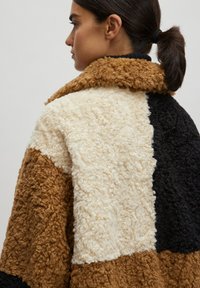 Braun, beige und schwarz gefärbte Jacke im Color-Blocking-Stil, gefertigt aus einem gemütlichen, strukturierten Stoff mit einem breiten Kragen und einer entspannten Passform.