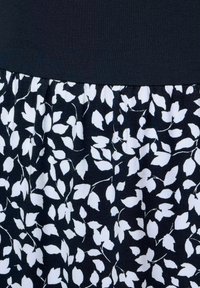 Czarno-biała sukienka z gładkim górnym partem, teksturowanym gorsetem oraz rozkloszowanym dołem ozdobionym małymi wzorami liści.