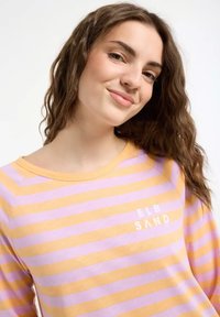 Gestreifte Langarmbluse in Lavendel und Gelb, mit Rundhalsausschnitt und dem aufgedruckten Text "ELB SAND" auf der Vorderseite. Aus weichem Baumwollstoff.