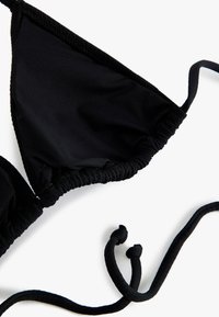 Zwarte stoffen bikini-top met driehoekige cups en verstelbare strikbandjes op een witte achtergrond.
