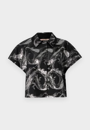 Czarny krótki top z metalicznym srebrnym abstrakcyjnym wzorem, krótki rękaw i spiczasty kołnierzyk. Gładka tekstura i widoczny zapięcie na guziki.