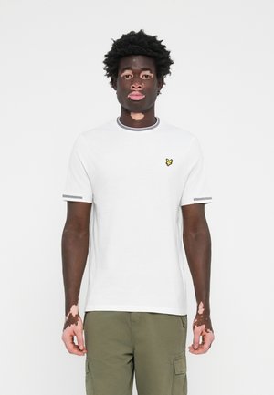 Vit kortärmad t-shirt med grå detaljer och en liten gul broderad fjäril-logotyp på bröstet. Slätt bomulls tyg.