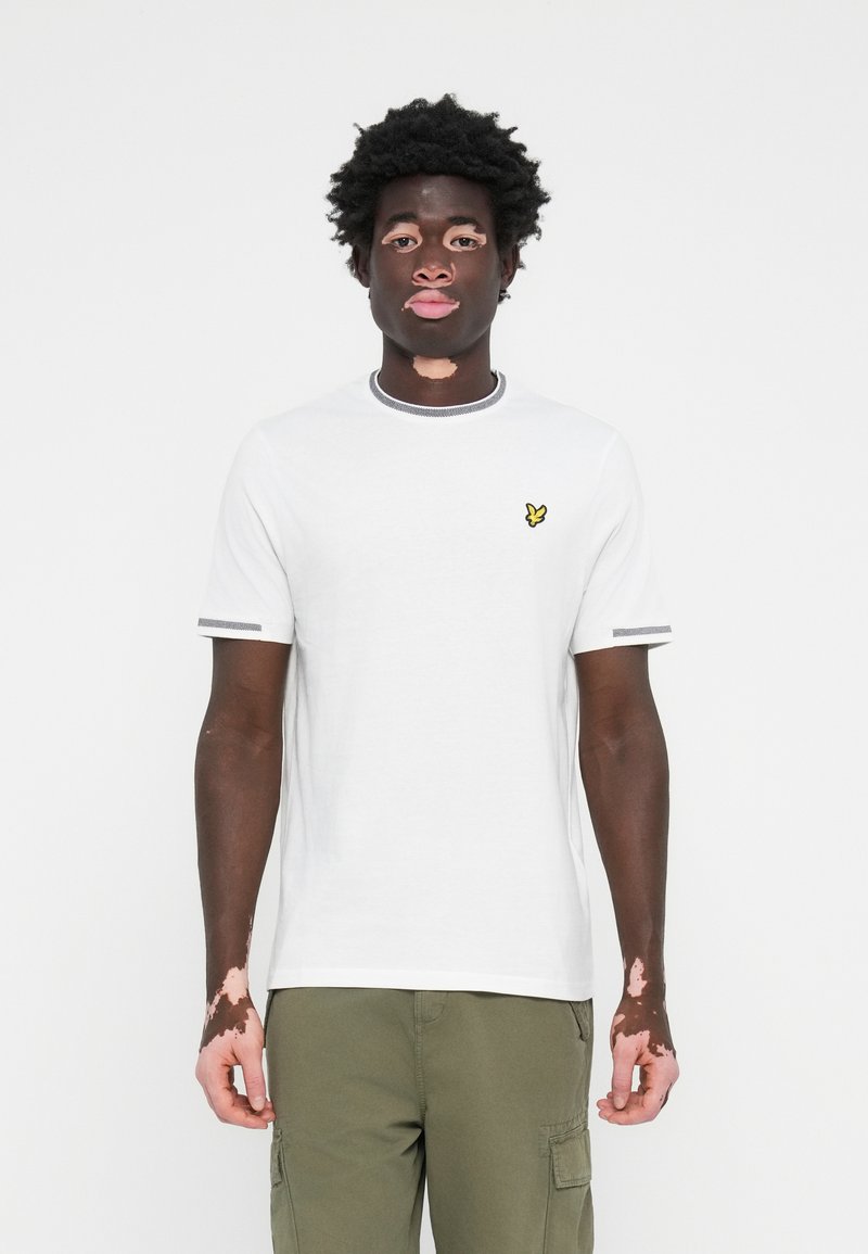 T-shirt blanc à manches courtes avec des finitions grises et un petit logo de papillon brodé en jaune sur la poitrine. Tissu en coton lisse.