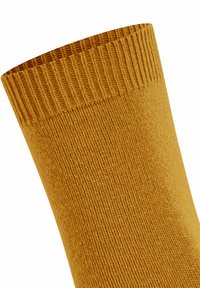 Ingrandimento di un polsino di calzino a coste di colore giallo senape con cuciture fini e bordo elastico.