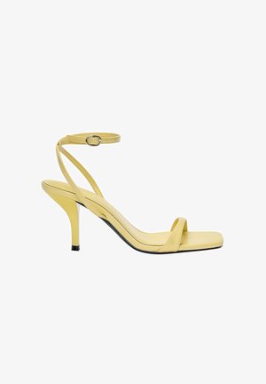 Sandale jaune à talon haut avec fine bride de cheville et boucle, bout ouvert et semelle carrée à l'avant.