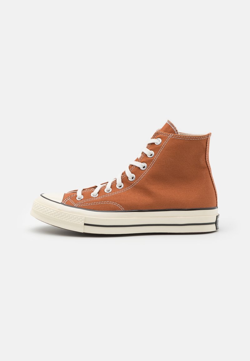 Höga sneakers i orange canvas med vita snörningar, kontrasterande sömmar och en svart gummisula med en texturerad tåhätta.