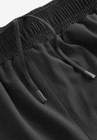 Shorts de sport noirs avec une taille élastique en tissu froncé, cordon de serrage pour un ajustement, et une texture lisse et douce.