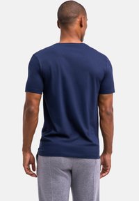 Granatowa koszulka z krótkim rękawem, z okrągłym dekoltem, wykonana z gładkiej bawełny, noszona z szarymi dresami. Prosty design, brak widocznych logotypów lub wzorów.