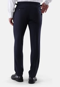 Marineblaue Anzughose mit maßgeschneiderter Passform, flacher Vorderseite, zwei Gesäßtaschen und glatter Textur. Kombiniert mit einem weißen Hemd und schwarzen Schuhen.