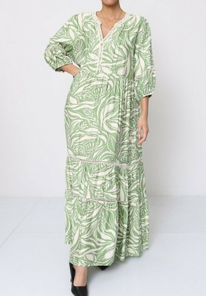 La robe maxi présente un motif de feuilles vertes et blanches, un décolleté en V, une taille froncée et une jupe à volants. Fabriquée en tissu léger avec des manches ballon.