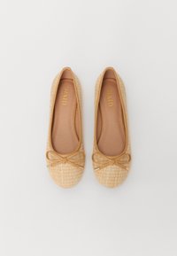 Ballerines en toile beige tissée, avec une fine bordure marron clair et un accent en nœud. La semelle intérieure est lisse avec le nom de la marque en doré.