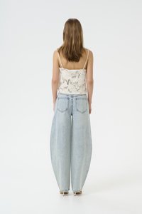 Cropped, light-colored, patterned tank top paired with oversized light blue denim jeans. Smooth texture, wide leg design, minimal detailing.