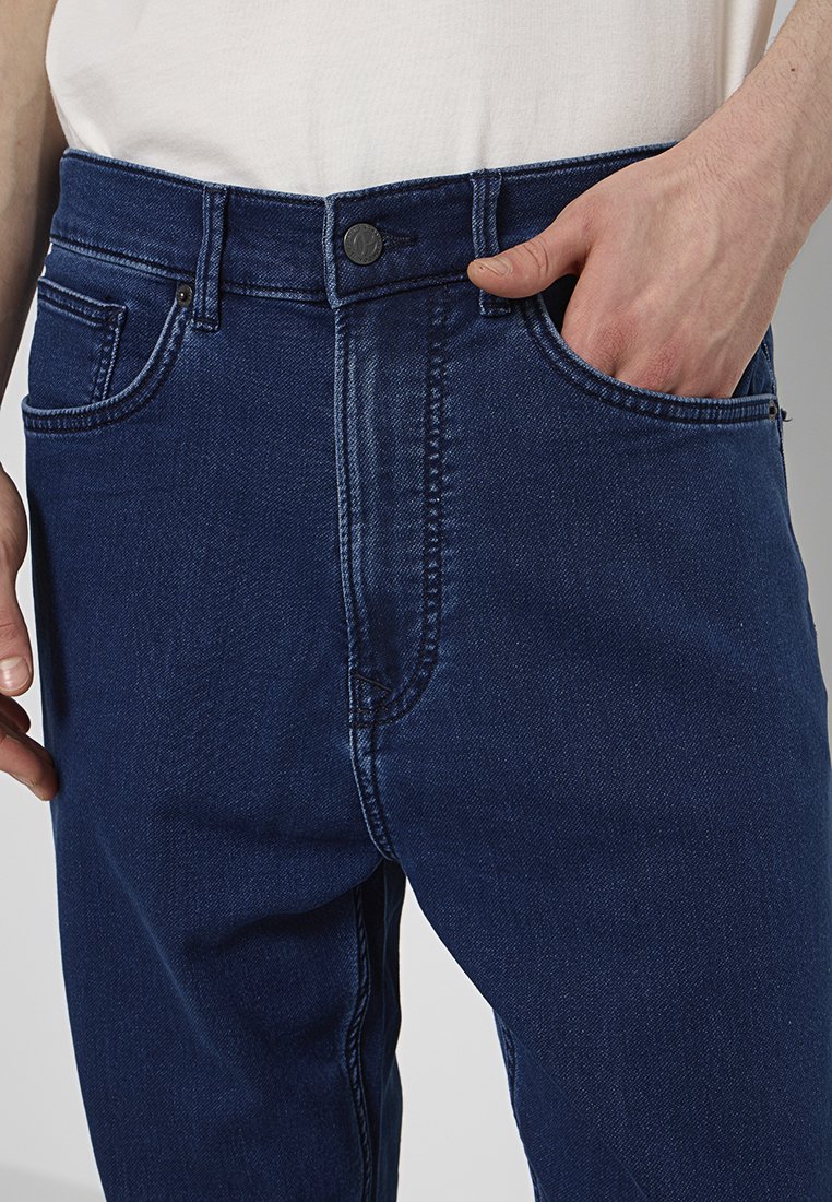 Jeans en denim bleu marine au design classique, avec des poches avant, une fermeture à bouton et des détails de couture subtils.