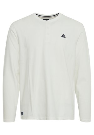 Bela majica s dolgimi rokavi iz bombaža z okroglim izrezom, zapenjanjem na tri gumbe in majhnim črnim trikotnim logom na prsih.
