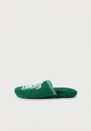 Pantofole verdi aperte sul retro in tessuto spugna con testa di tigre ricamata in bianco sulla parte superiore, viste di lato su uno sfondo semplice.