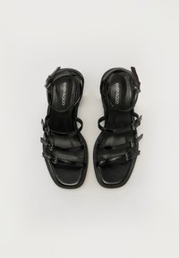 Black sandals with multiple narrow straps, square toe, and a slight heel. Made of smooth leather with buckle accents.