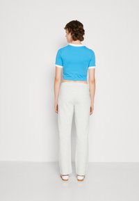 Blå kort t-skjorte med hvit kant, kombinert med lysegrå joggebukser. Outfitten har en avslappet passform og myke, glatte teksturer.