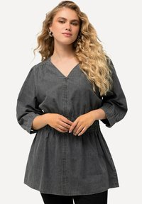 Tunica in denim grigia con scollatura a V, maniche puff 3/4, vita arricciata e dettagli di cucitura discreti. Tessuto morbido e leggero con una vestibilità rilassata.