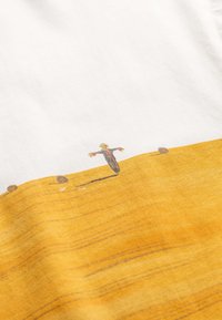 Katoenen t-shirt met een witte bovensectie en een gele ondersectie, met een getextureerd, geïllustreerd design van een vogelverschrikker in het midden.