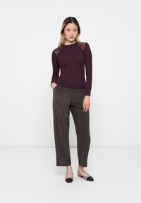 Bordeaux lange mouw top met kantaccenten op de schouders, gecombineerd met grijze wijde broek en zwart-beige tweekleurige flats.