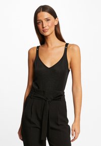 Haut sans manches noir avec un décolleté en V, fabriqué à partir d'un tissu scintillant. Présente des accents décoratifs sur les bretelles et une coupe ajustée.
